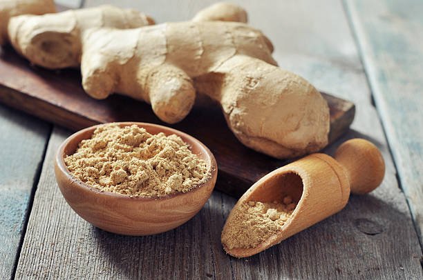 Fresh ginger root and ground ginger spice on wooden background